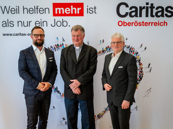 v.l.: Mag. Stefan Pimmingstorfer, Bischof Dr. Manfred Scheuer und Franz Kehrer, MAS. Drei Männer stehen vor einem Werbeplakat
